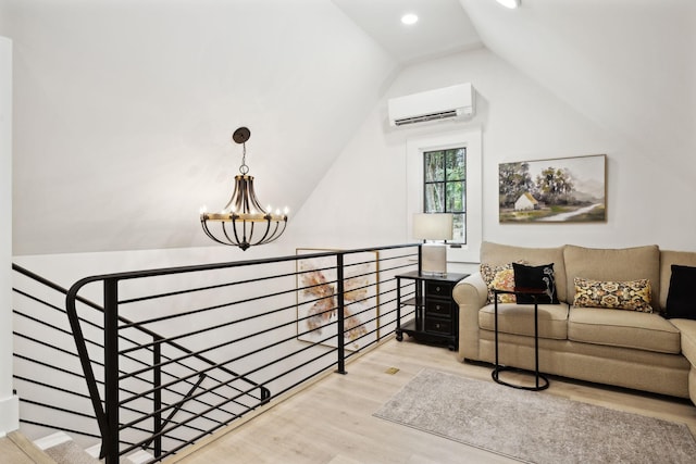 living room featuring light hardwood / wood-style floors, a wall mounted air conditioner, an inviting chandelier, and vaulted ceiling