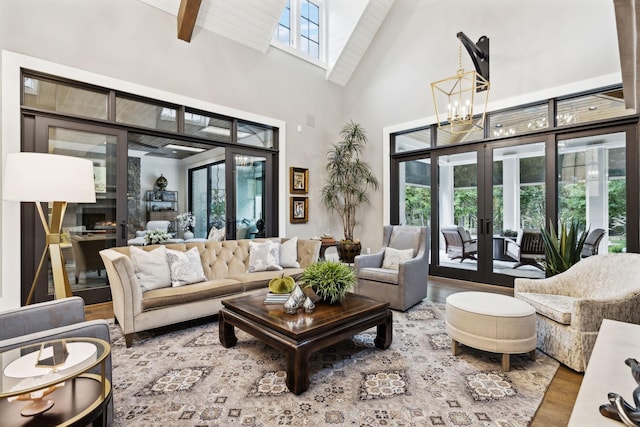 living room featuring french doors, a high ceiling, an inviting chandelier, and a healthy amount of sunlight