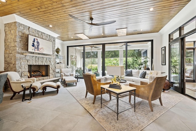 sunroom featuring ceiling fan, wooden ceiling, and a stone fireplace