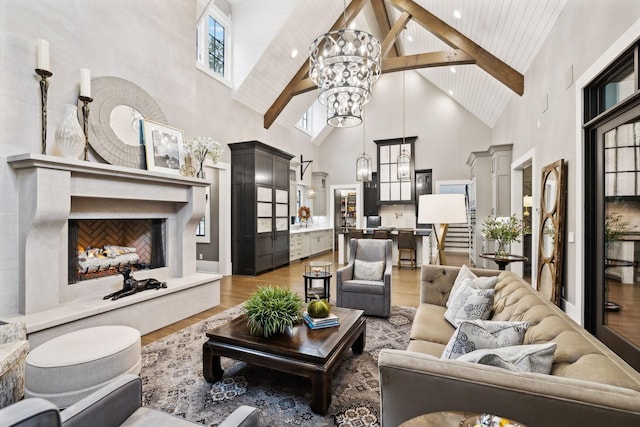 living room with a high end fireplace, high vaulted ceiling, a notable chandelier, and light hardwood / wood-style floors