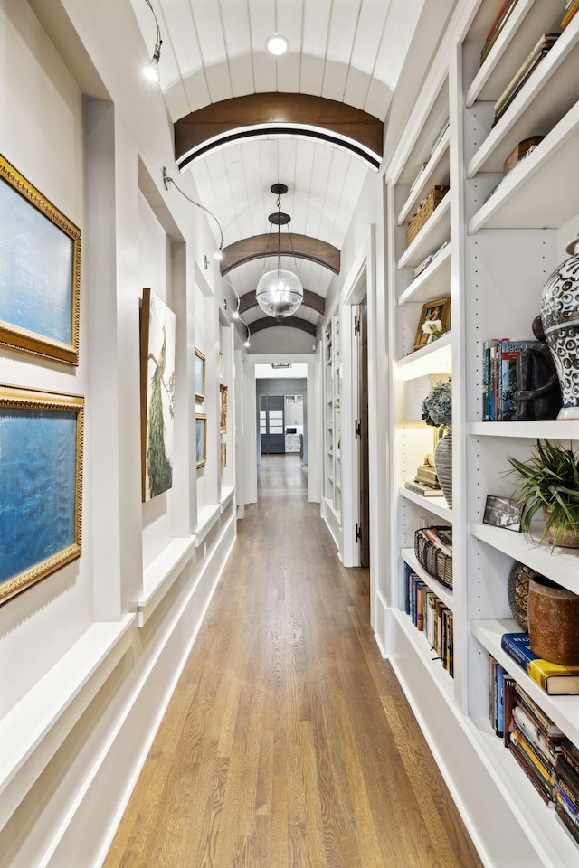 hallway with brick ceiling, vaulted ceiling with beams, and wood-type flooring