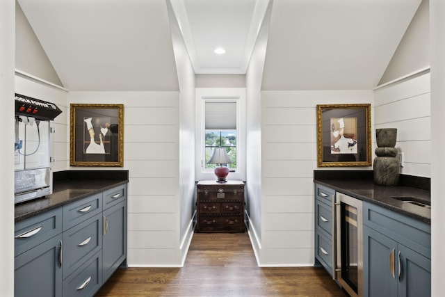 kitchen featuring wooden walls, vaulted ceiling, beverage cooler, dark stone counters, and dark wood-type flooring