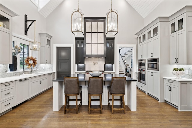 kitchen featuring a kitchen island, high vaulted ceiling, backsplash, and hanging light fixtures