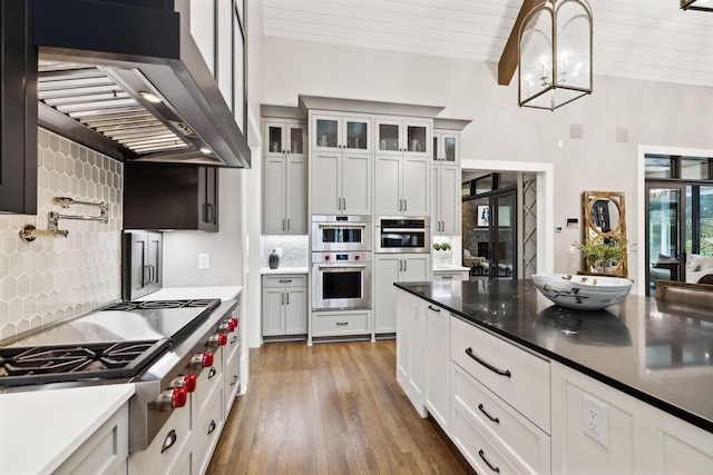 kitchen featuring stainless steel appliances, exhaust hood, and white cabinetry