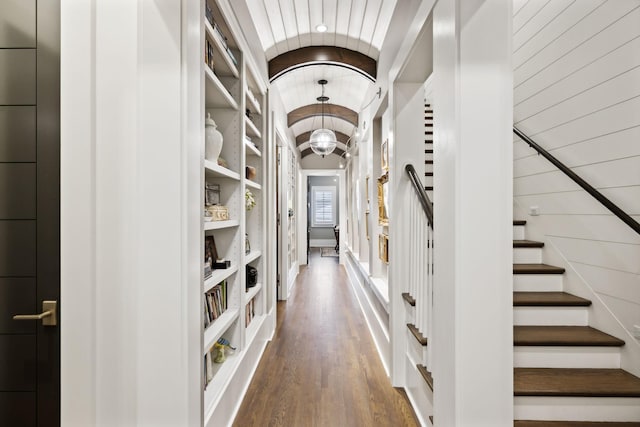 corridor featuring wood walls, built in shelves, and wood-type flooring