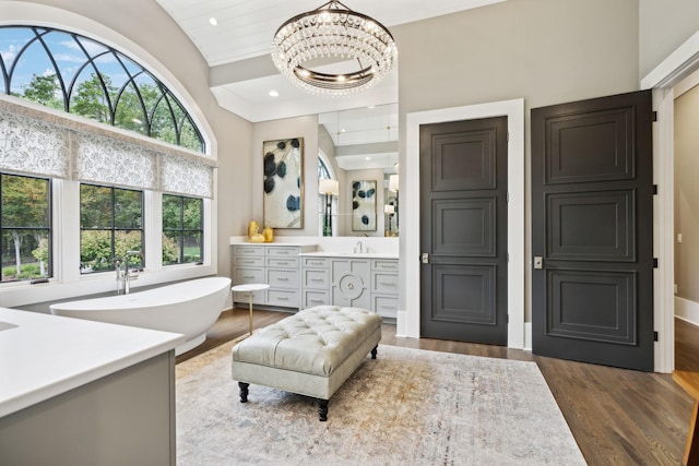 bathroom featuring vaulted ceiling, a tub to relax in, an inviting chandelier, wood-type flooring, and vanity