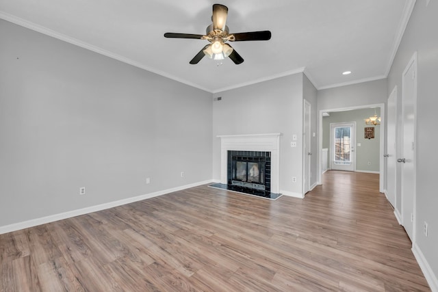 unfurnished living room with ornamental molding, light wood-type flooring, a tile fireplace, and ceiling fan with notable chandelier