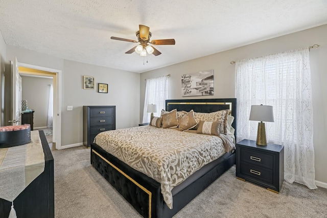 bedroom featuring a textured ceiling, ceiling fan, and light carpet