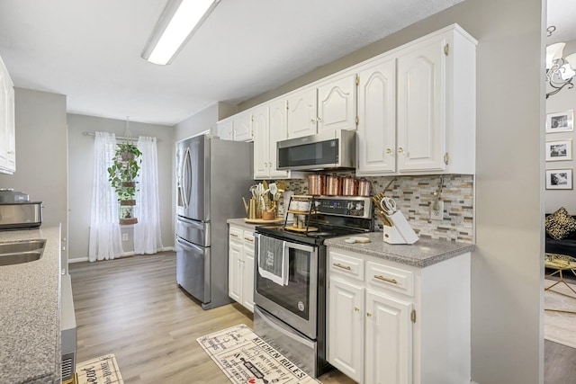 kitchen with sink, appliances with stainless steel finishes, tasteful backsplash, and white cabinetry