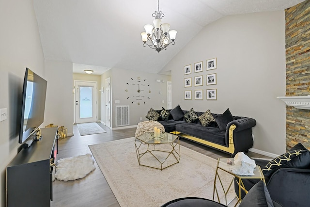 living room featuring a notable chandelier, vaulted ceiling, and wood-type flooring