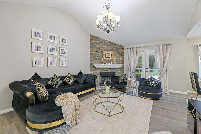 living room with a stone fireplace, an inviting chandelier, french doors, and hardwood / wood-style floors