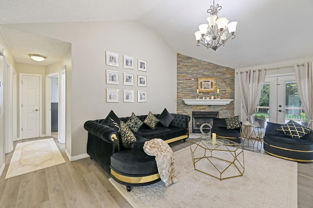 living room with lofted ceiling, french doors, hardwood / wood-style floors, a chandelier, and a stone fireplace