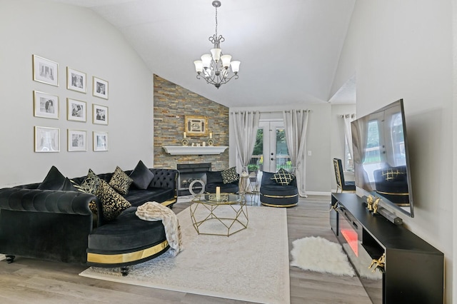 living room with hardwood / wood-style floors, vaulted ceiling, a chandelier, french doors, and a fireplace