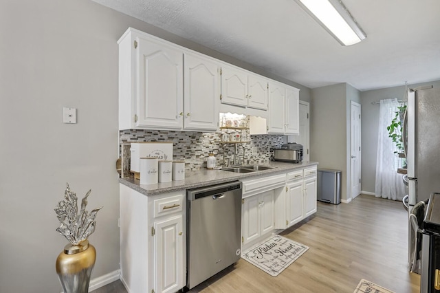 kitchen with white cabinets, appliances with stainless steel finishes, light hardwood / wood-style flooring, and sink