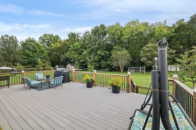 wooden terrace with a grill, a lawn, and a trampoline