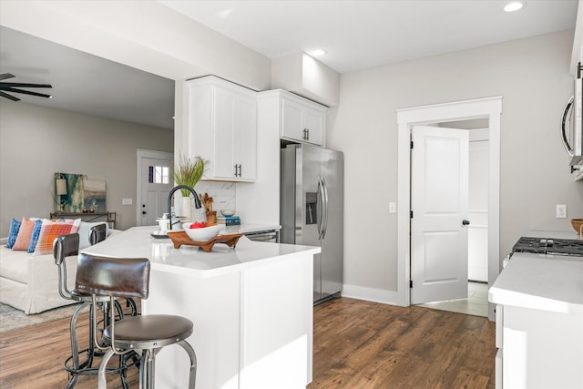 kitchen with stainless steel appliances, white cabinetry, ceiling fan, kitchen peninsula, and dark wood-type flooring