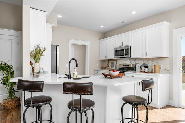 kitchen featuring appliances with stainless steel finishes, white cabinetry, a breakfast bar area, and sink