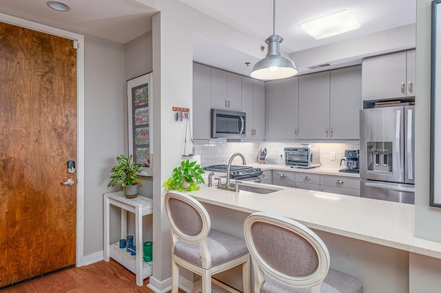 kitchen featuring stainless steel appliances, a kitchen bar, sink, and pendant lighting