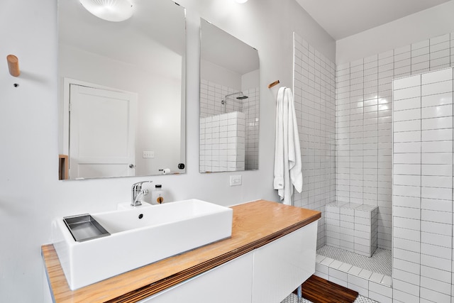 bathroom with tiled shower and vanity