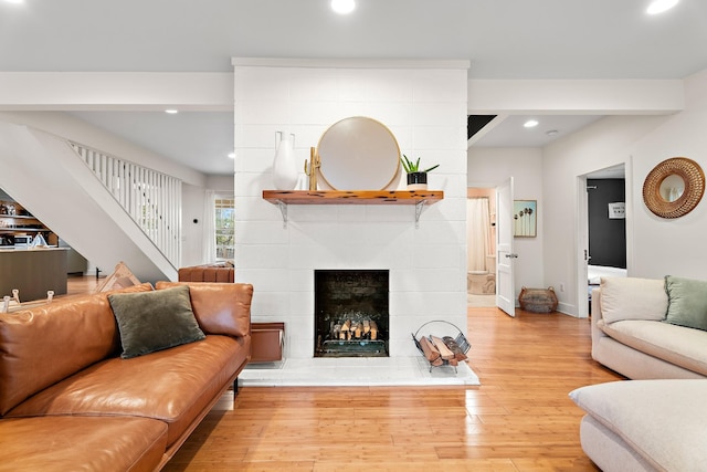 living room with a tiled fireplace and light hardwood / wood-style flooring