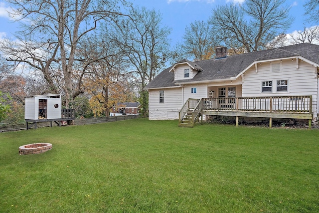 back of property featuring a lawn, a deck, and a fire pit