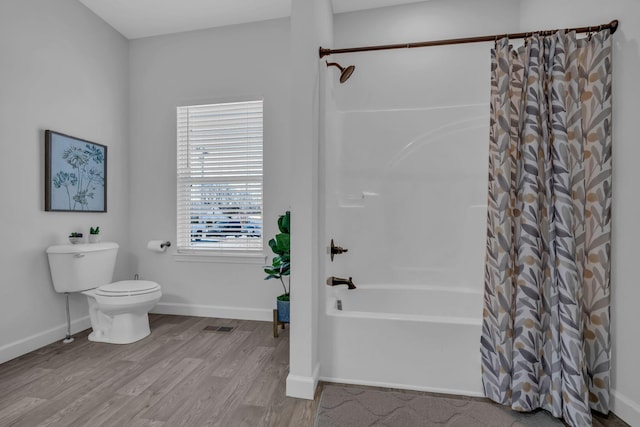 bathroom with toilet, hardwood / wood-style floors, and shower / bath combo with shower curtain