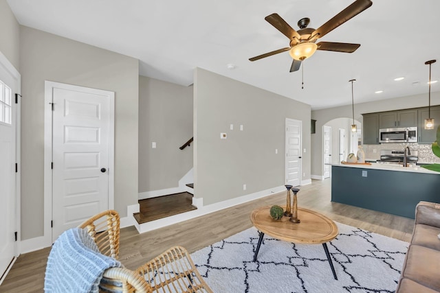 living room with ceiling fan, light wood-type flooring, and a wealth of natural light