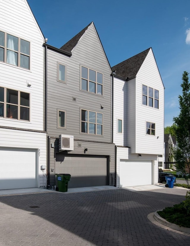 view of front facade featuring a wall unit AC and a garage