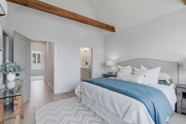 bedroom featuring light hardwood / wood-style floors, ensuite bathroom, and lofted ceiling with beams