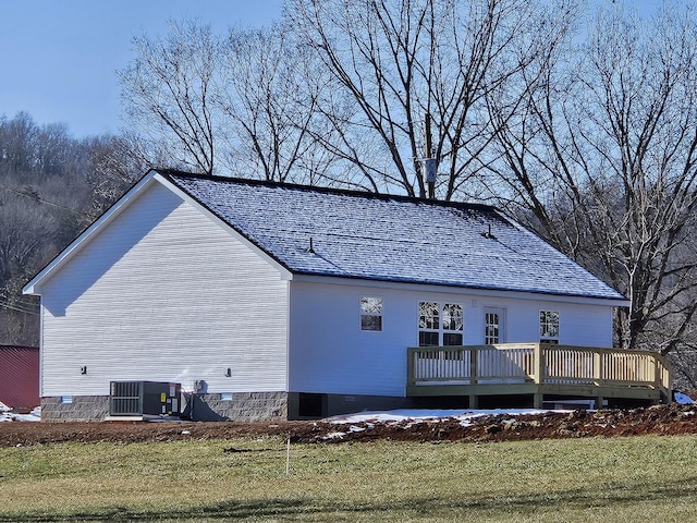 rear view of house featuring cooling unit, a deck, and a yard