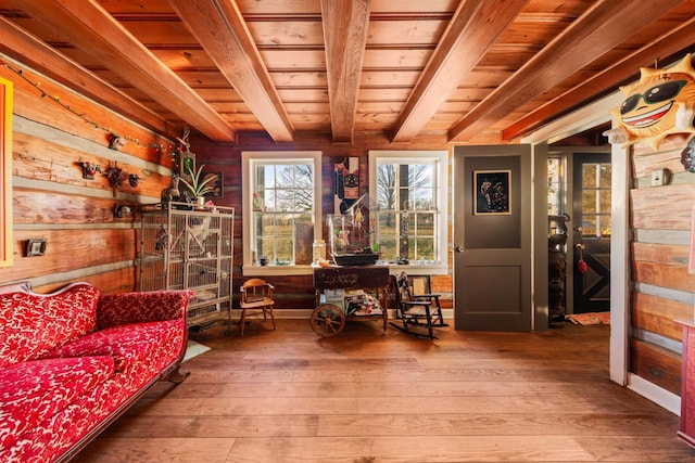 living area with wooden walls, hardwood / wood-style floors, wooden ceiling, and beamed ceiling