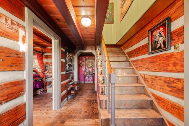 stairs featuring wooden walls, wood ceiling, and hardwood / wood-style floors