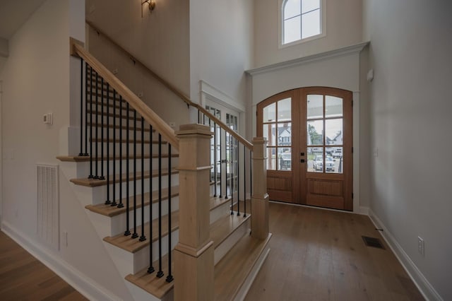 entrance foyer featuring a high ceiling, french doors, and wood-type flooring