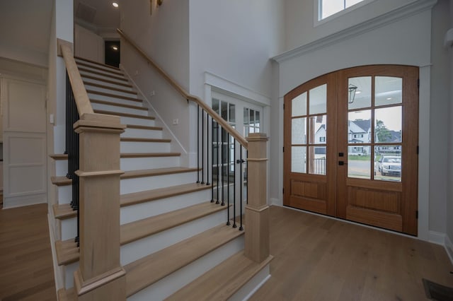 entryway with a high ceiling, french doors, light hardwood / wood-style floors, and a wealth of natural light