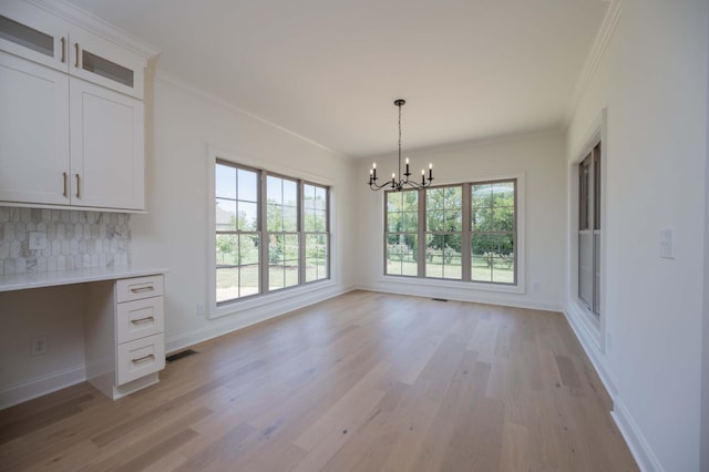 unfurnished dining area with light hardwood / wood-style floors, ornamental molding, and a healthy amount of sunlight