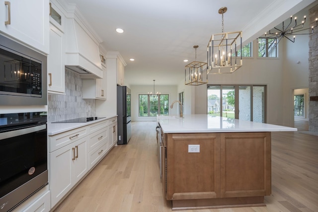 kitchen with white cabinets, a large island, black appliances, and hanging light fixtures