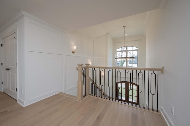 hallway with french doors, an inviting chandelier, ornamental molding, and light hardwood / wood-style flooring