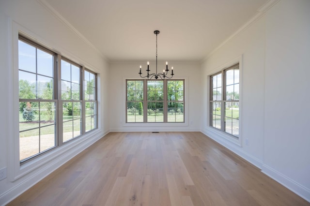 unfurnished dining area featuring crown molding, light hardwood / wood-style flooring, and a chandelier