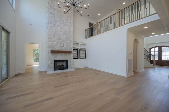 unfurnished living room featuring a towering ceiling, a fireplace, plenty of natural light, and crown molding