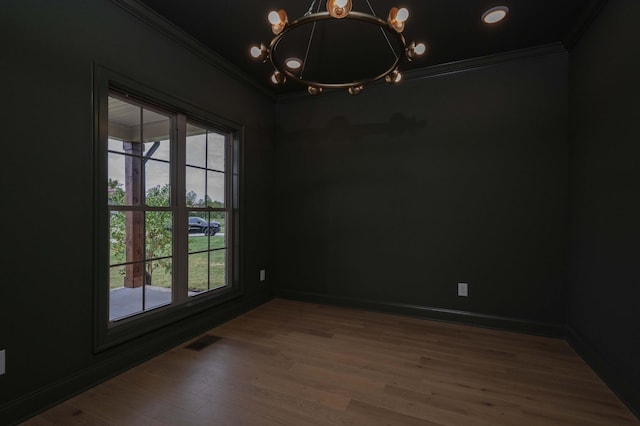 unfurnished room with crown molding, hardwood / wood-style floors, a wealth of natural light, and a notable chandelier