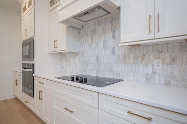 kitchen featuring white cabinets, stainless steel oven, custom range hood, tasteful backsplash, and black electric cooktop