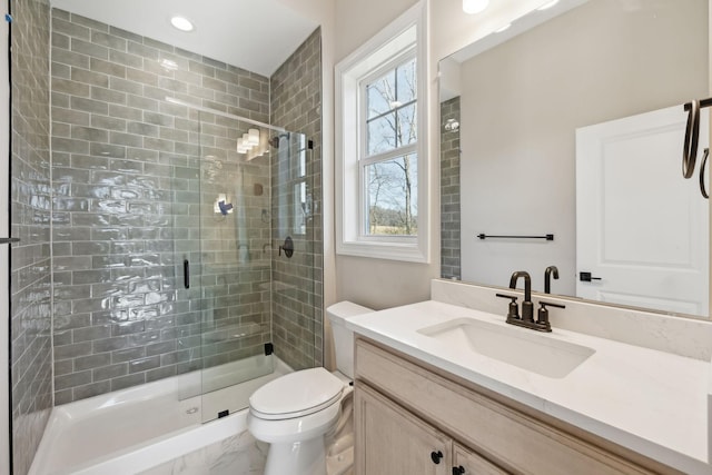 bathroom with toilet, vanity, and a shower with shower door