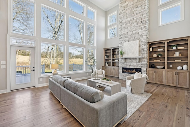 living room featuring a high ceiling, a fireplace, light wood-type flooring, and crown molding