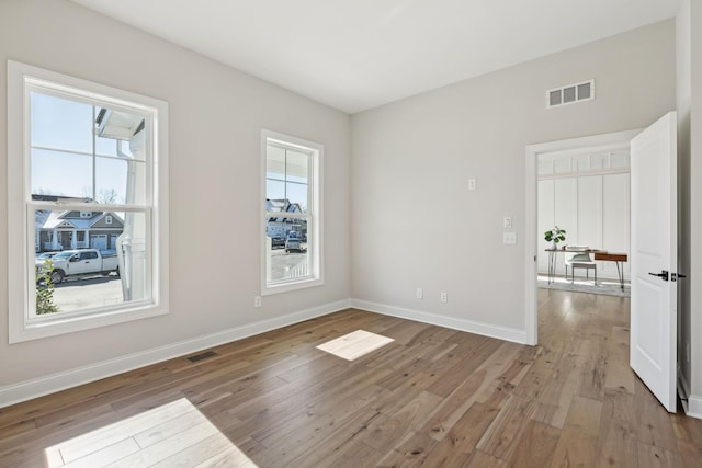 unfurnished room featuring light wood-type flooring and a healthy amount of sunlight