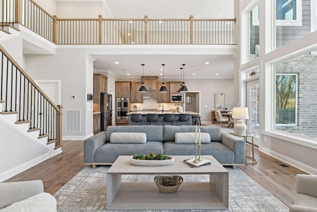 living room featuring ornamental molding, a towering ceiling, and wood-type flooring