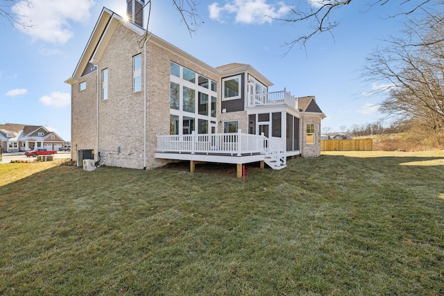 back of property featuring central AC unit, a wooden deck, a sunroom, and a lawn