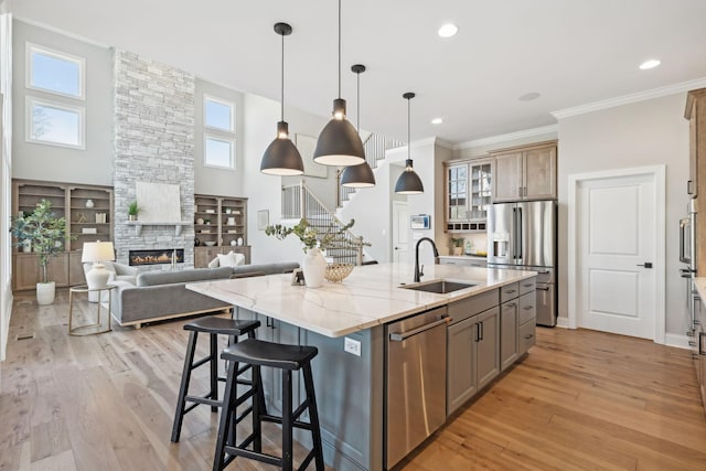 kitchen with stainless steel appliances, sink, a large island, a fireplace, and light stone countertops