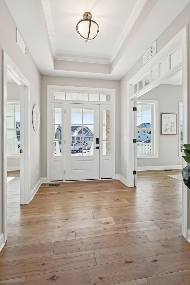 entryway featuring light hardwood / wood-style floors, crown molding, and a tray ceiling