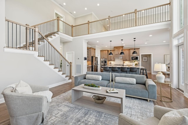 living room featuring ornamental molding, hardwood / wood-style floors, and a towering ceiling