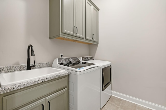 laundry room featuring sink, washer and dryer, light tile patterned floors, and cabinets